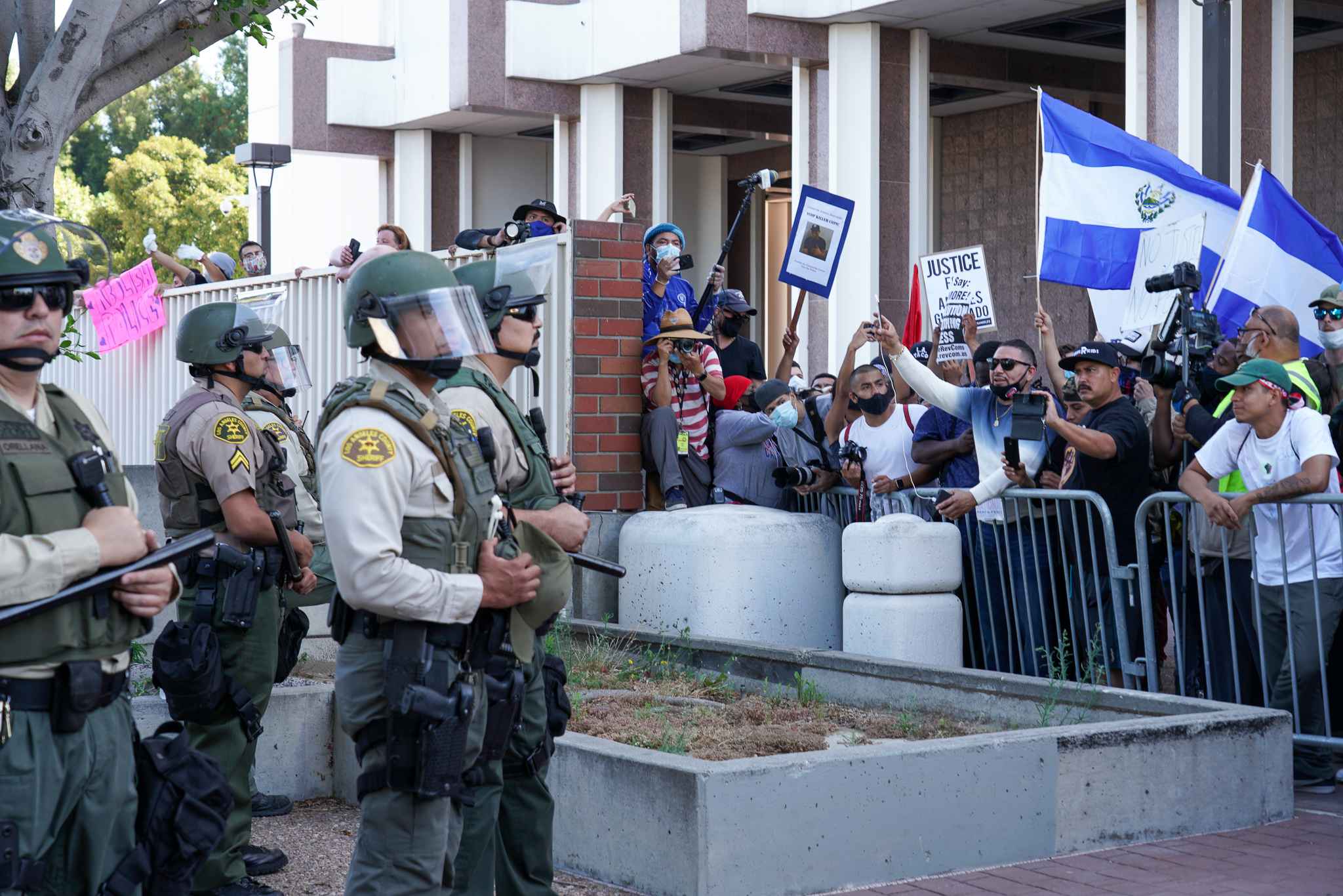 Andres Guardado's uncle Noe Abarca (arm raised, center, in white and blue sweater) demanding answers from deputies outside the Compton Sheriff Station. Photo: Francisco Lozano