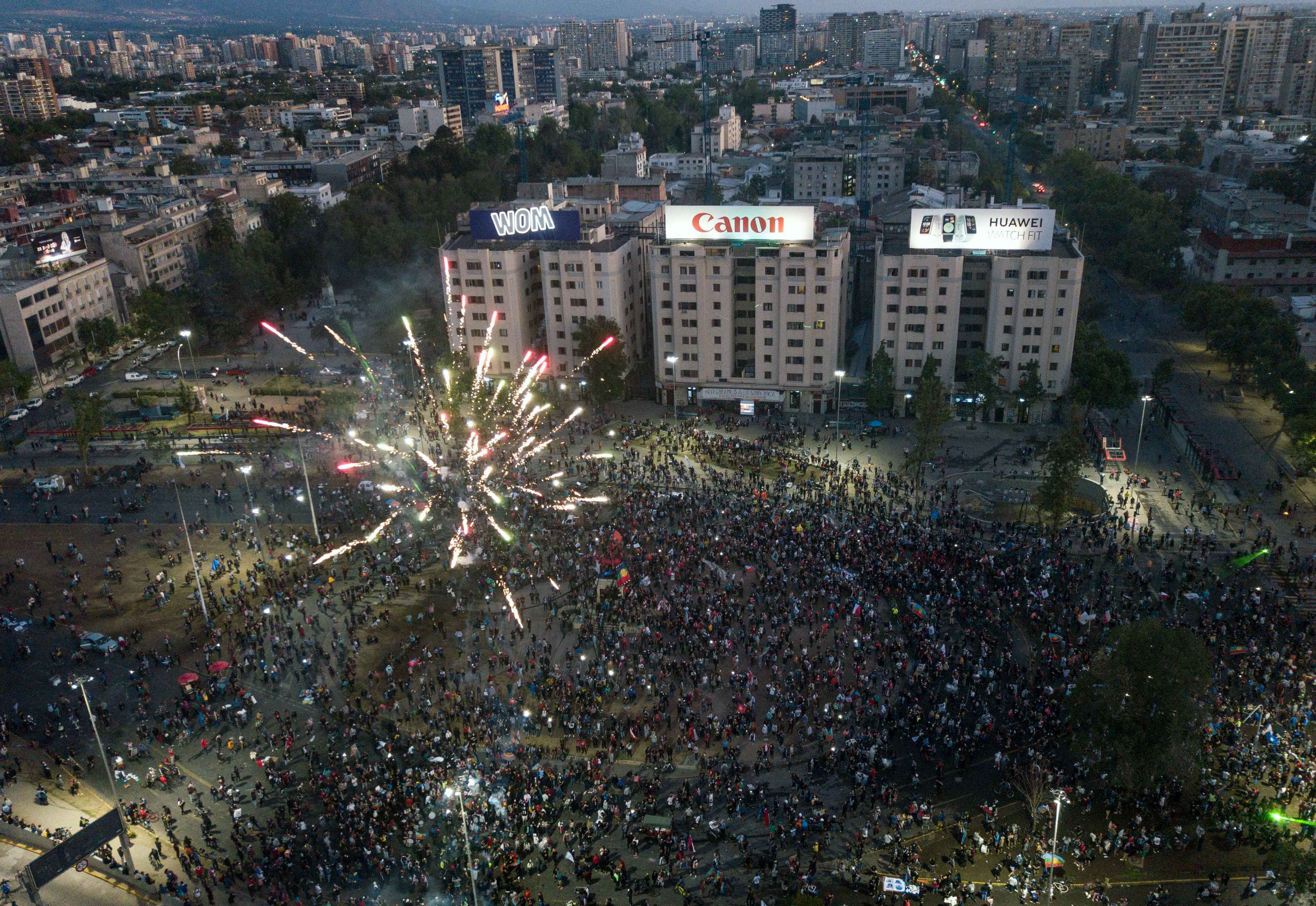 Aerial view showing demonstrators supporting the reform of the Chilean constitution waiting for the referendum official results at Plaza Italia square in Santiago on October 25, 2020. - The campaign to replace Chile's dictatorship-era constitution held a big lead in Sunday's referendum, partial results showed. The "Approve" vote to throw-out a constitution seen as underpinning the nation's glaring inequalities led by 77.26 percent to 22.74 percent, with 11 percent of the votes counted. (Photo by JAVIER TORRES / AFP)