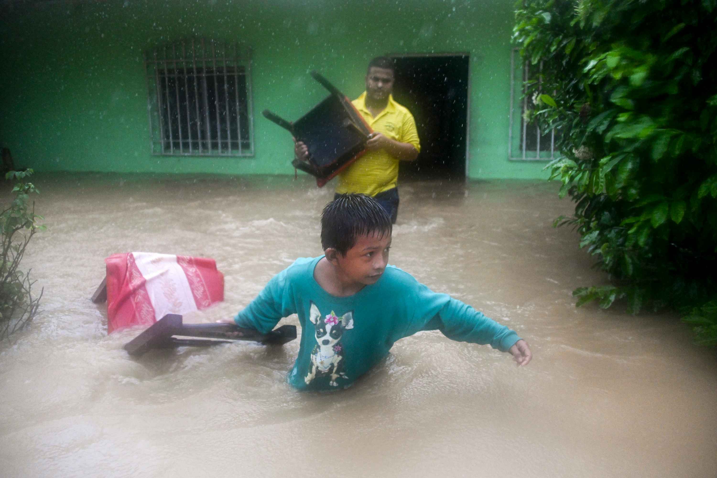 A boy and a man save chairs from a flooded house due to the heavy rains caused by Hurricane Eta, now degraded to a tropical storm, in Puerto Barrios, Izabal 310 km north Guatemala City on November 5, 2020. - At least four people, including two children, died in landslides as tropical storm Eta swept through Guatemala, civil protection officials said Thursday. The deaths brought the toll in Central America to eight after Eta tore into northern Nicaragua as a Category 4 hurricane on Tuesday causing mudslides that killed two miners, as well as two young girls in neighboring Honduras. (Photo by Johan ORDONEZ / AFP)