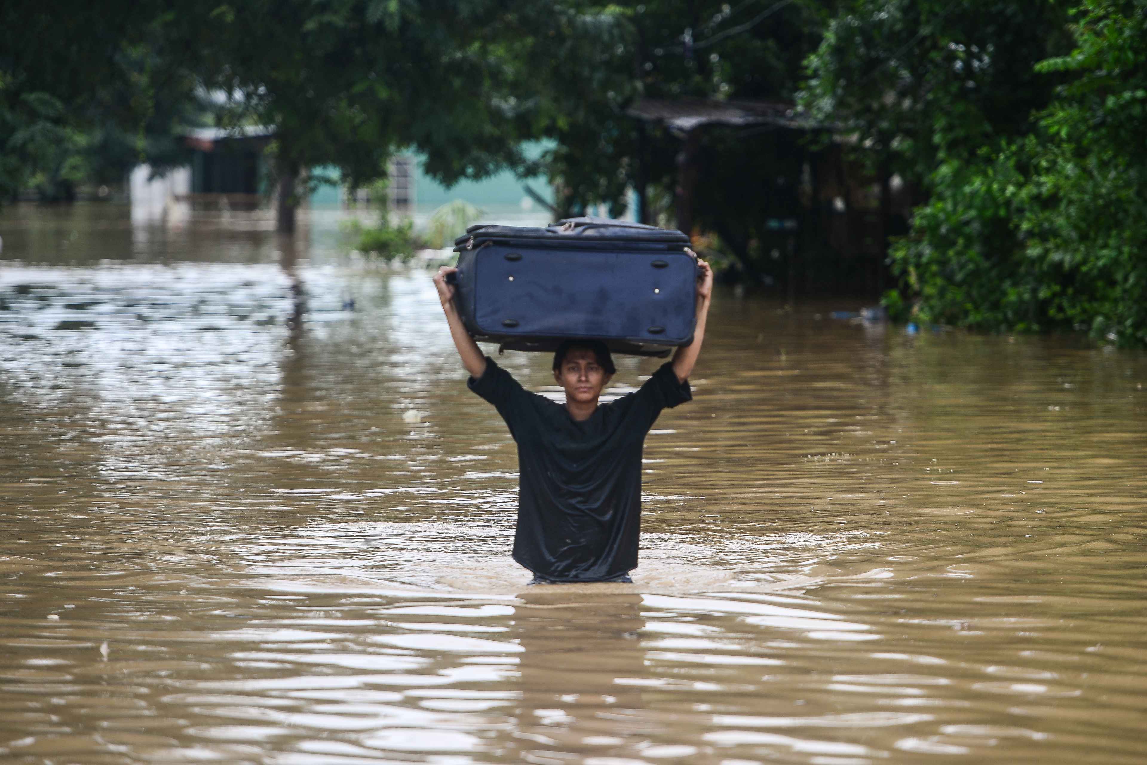 A woman wades carrying a luggage through a flooded street after the overflowing of the Ulua River in the municipality of El Progreso, department of Yoro, Honduras on November 5, 2020. due to the heavy rains caused by Hurricane Eta, now degraded to a tropical storm. - Eta devastated coastal areas of northern Nicaragua before weakening to a tropical depression by Wednesday as it pushed north through Honduras, Guatemala and Costa Rica. (Photo by Orlando SIERRA / AFP)