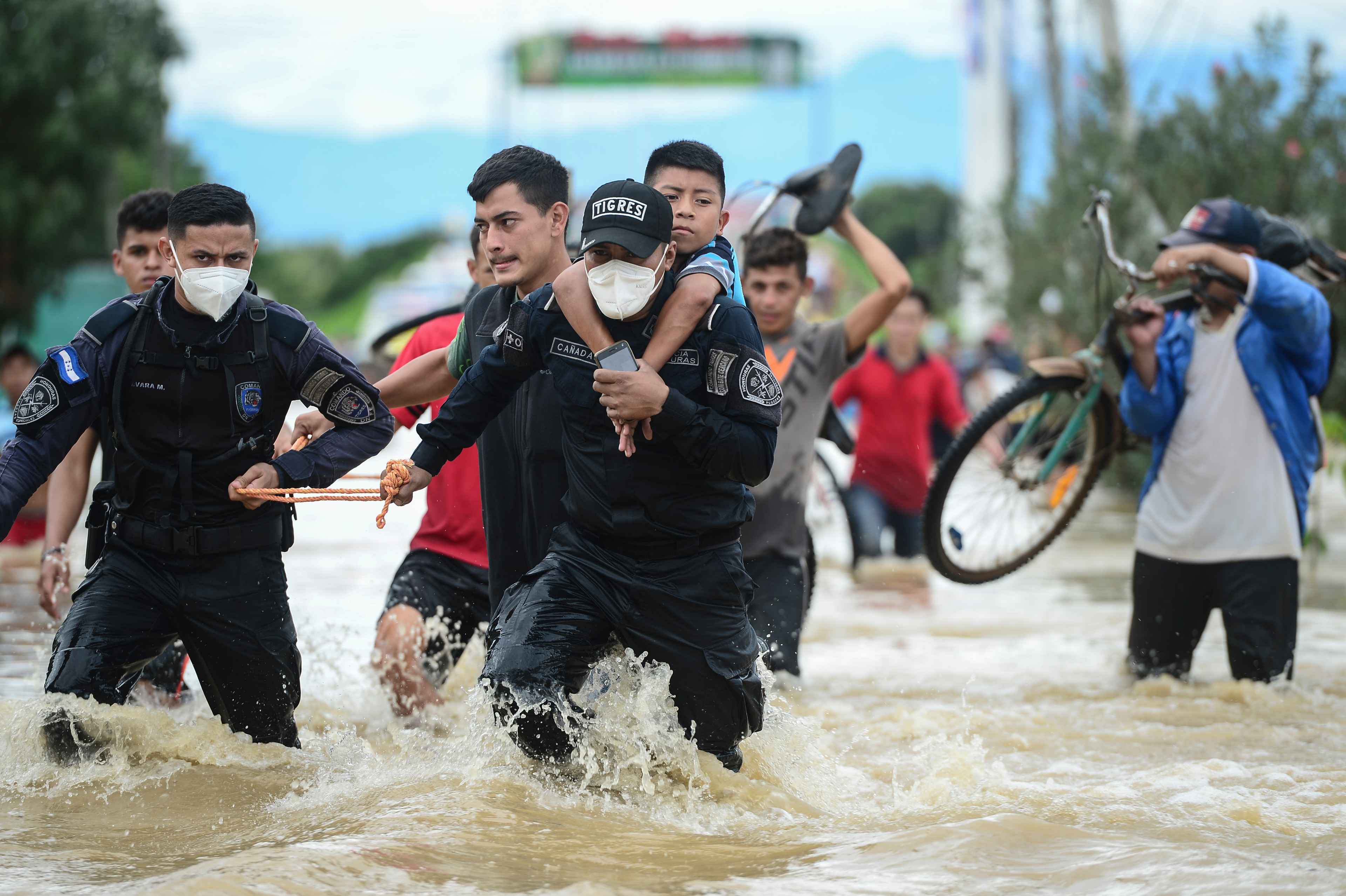 Honduras police officers help to evacuate people after the overflow of Ulua river due to the heavy rains caused by Hurricane Eta, now degraded to a tropical storm, in the city of El Progreso, department of Yoro, 260 kms north of Tegucigalpa, on November 5, 2020. (Photo by Orlando SIERRA / AFP)