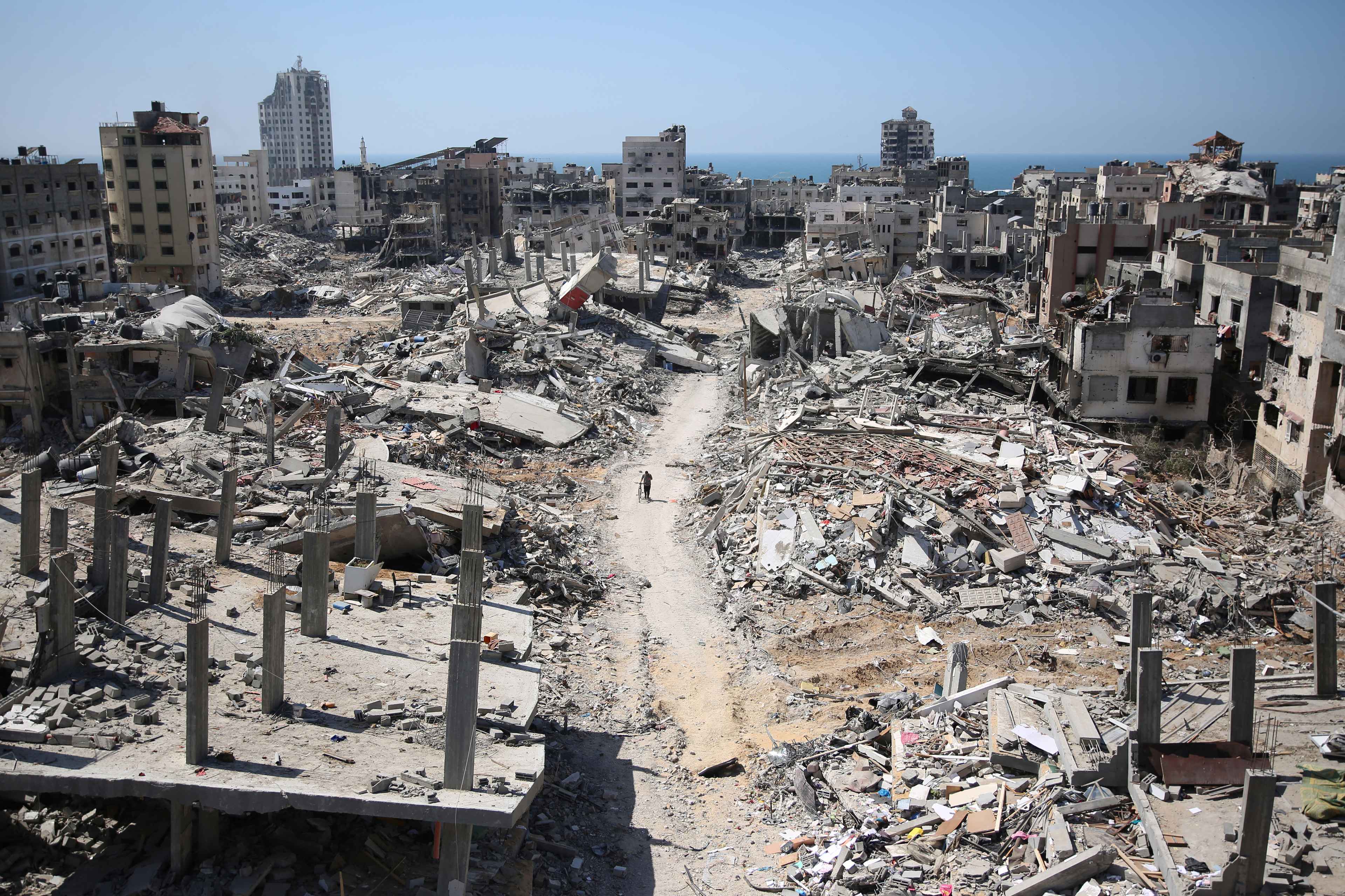 A man pushes a bycicle along as he walks amid building rubble in the devastated area around Gaza's Al-Shifa hospital on April 3, 2024. Photo AFP