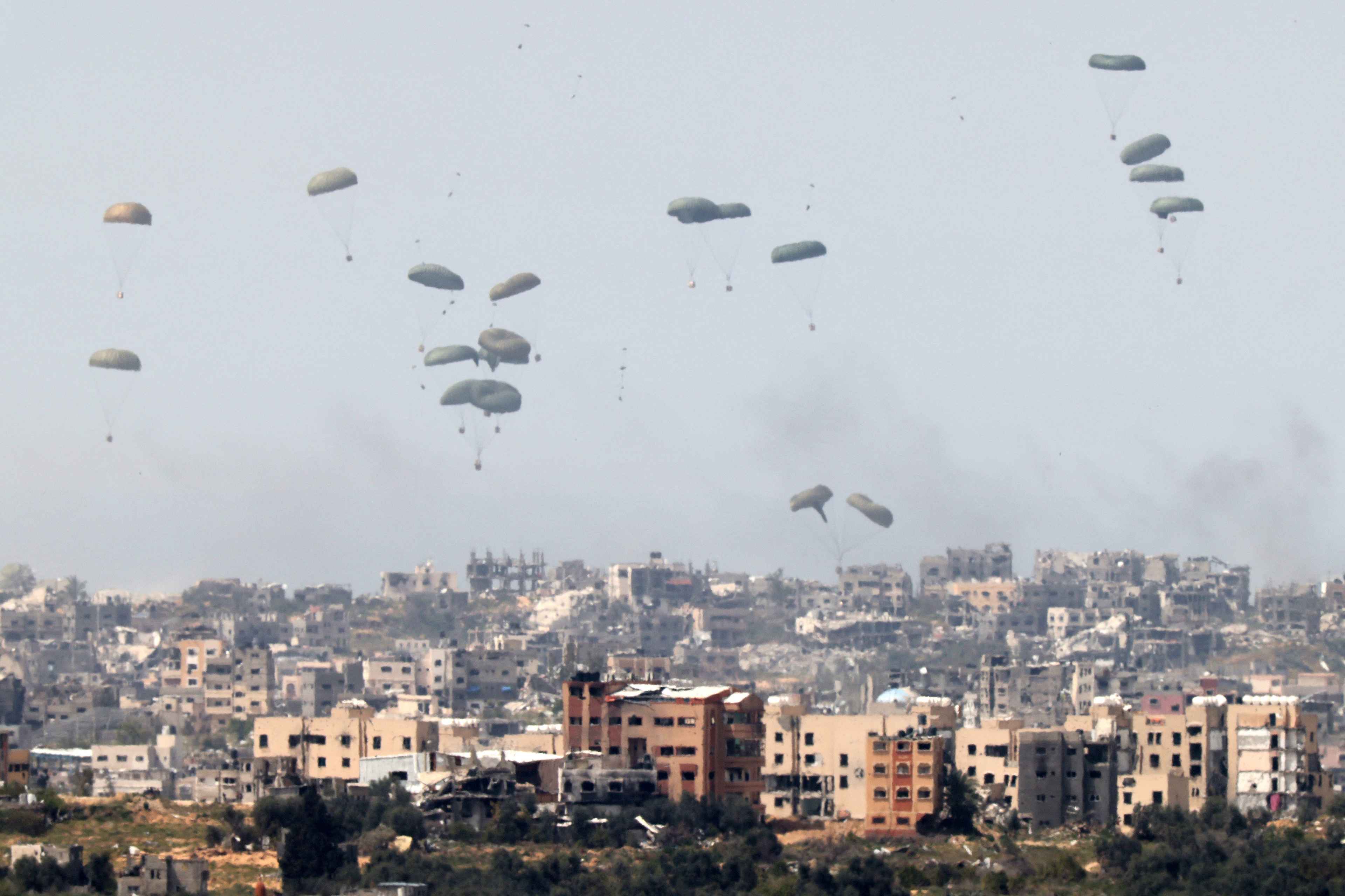 This picture taken from Israel's southern border with the Gaza Strip shows a military aircraft releasing parachutes of humanitarian aid over the besieged Palestinian territory on March 27, 2024. Photo Jack Guez/AFP