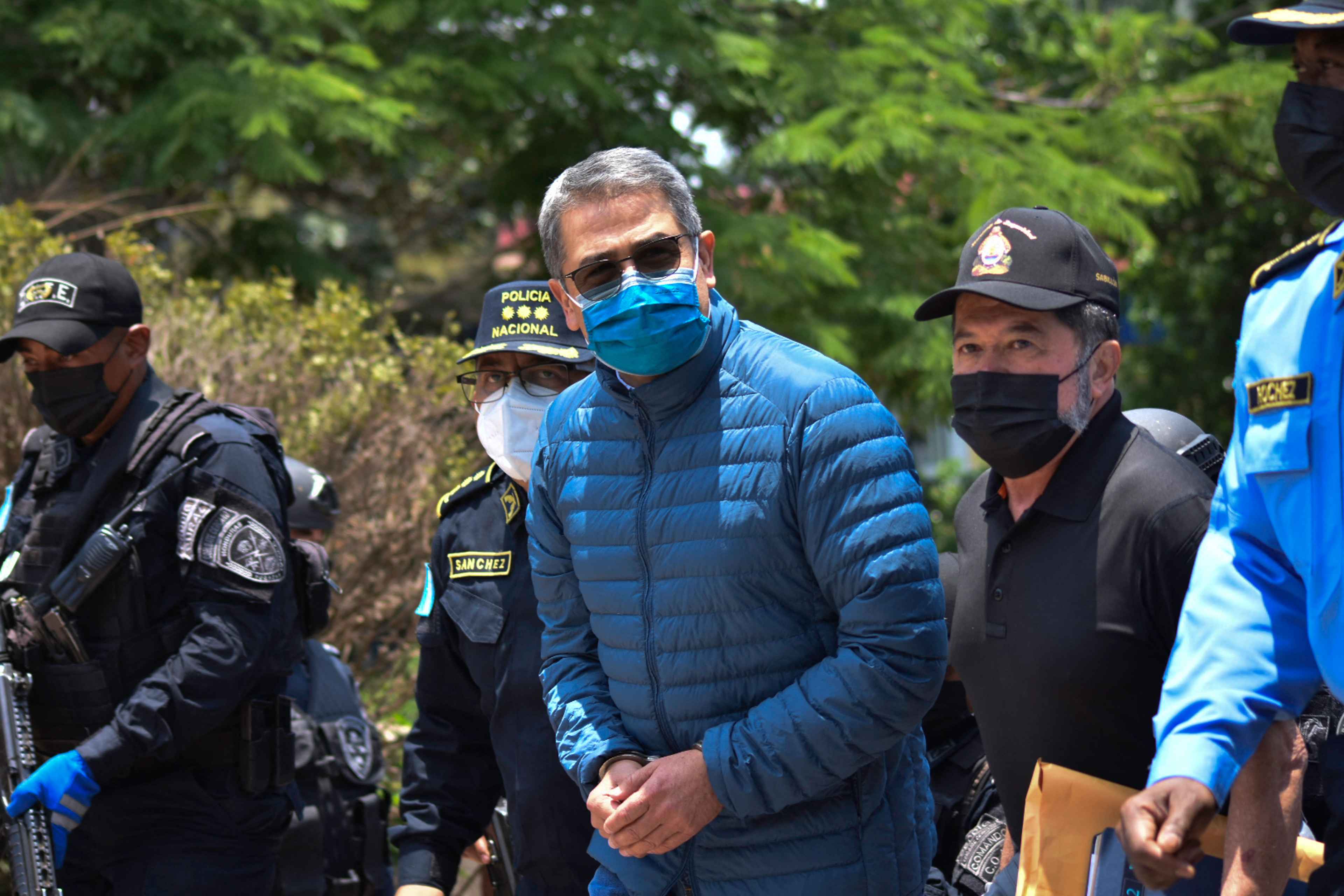 El expresidente de Honduras Juan Orlando Hernández es escoltado por agentes policiales en la Dirección Nacional de Fuerzas Especiales de Honduras antes de su extradición a Estados Unidos para enfrentar cargos relacionados con el tráfico de drogas. Tegucigalpa, 21 de abril de 2022. Foto de El Faro: AFP. 
