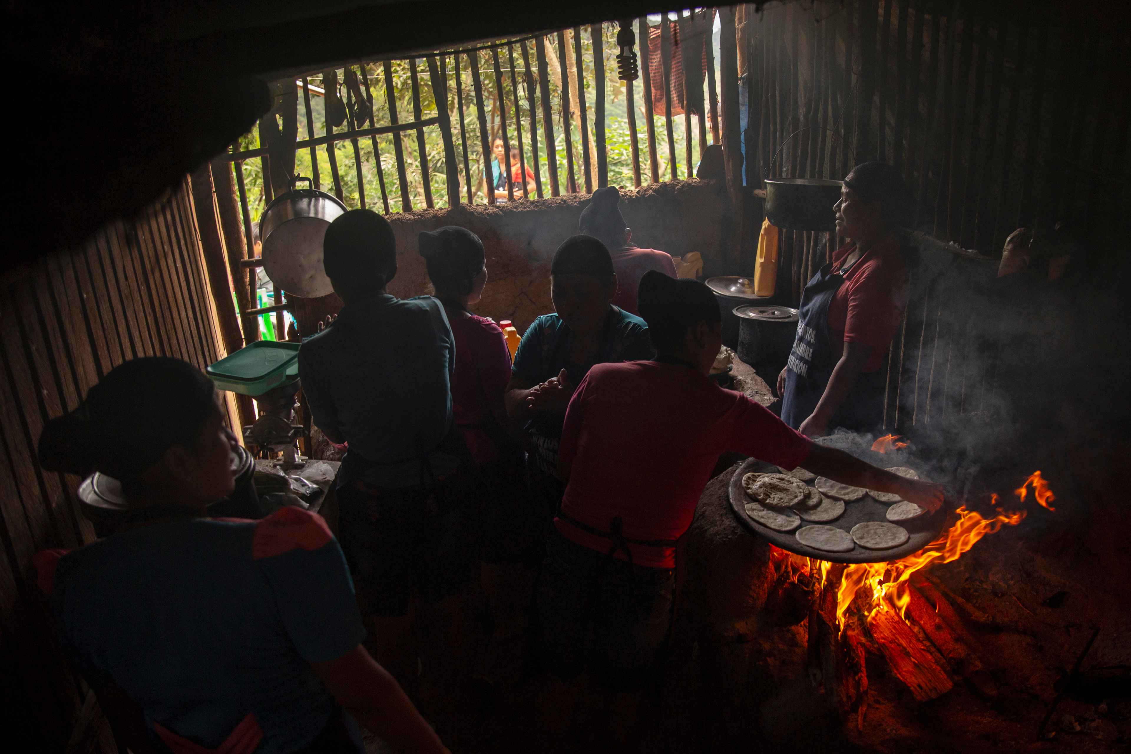 Seven women prepare food for more than 25 children in the home of Vitalina Morales, one of those who takes part in the community kitchen. The women involved in the communal garden project divy up work aimed at improving their children's lives. The two gardens require the work of 50 people, 40 of them women, and the participants have also constructed a clinic and expanded a classroom that no longer had room for more children.